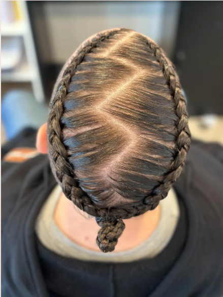 Top view of a person's head with hair styled in two French braids that connect into a small braid at the back