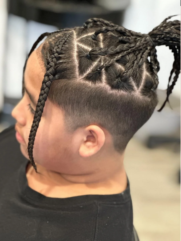 Side view of a young girl with braided hairstyle featuring geometric patterns and dreadlocks.