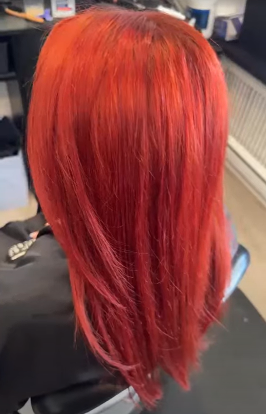 Side view of a person with vibrant red, straight, shoulder-length hair.
