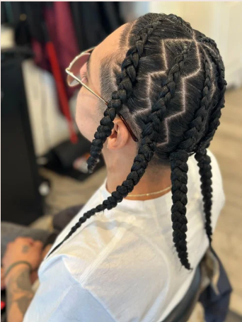 Side view of a person with braided hair in a unique pattern, wearing glasses and a face mask.