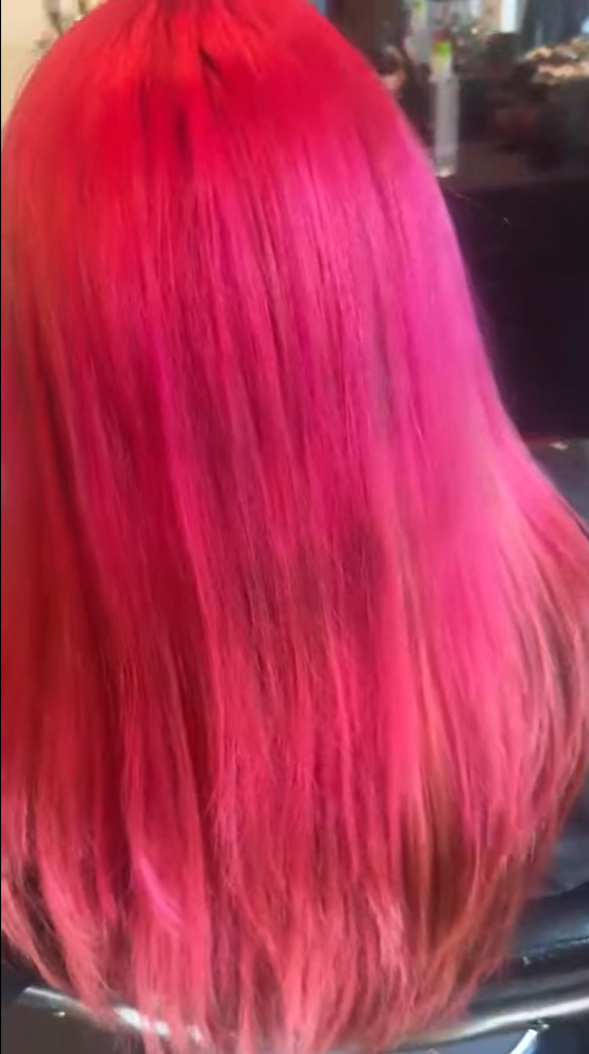A person with long, straight hair dyed in shades of pink and red.
