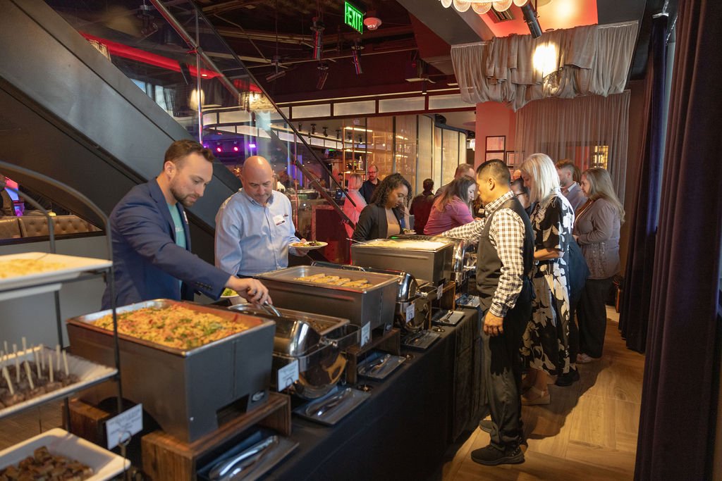 People serving themselves food at a buffet in a restaurant or event space.