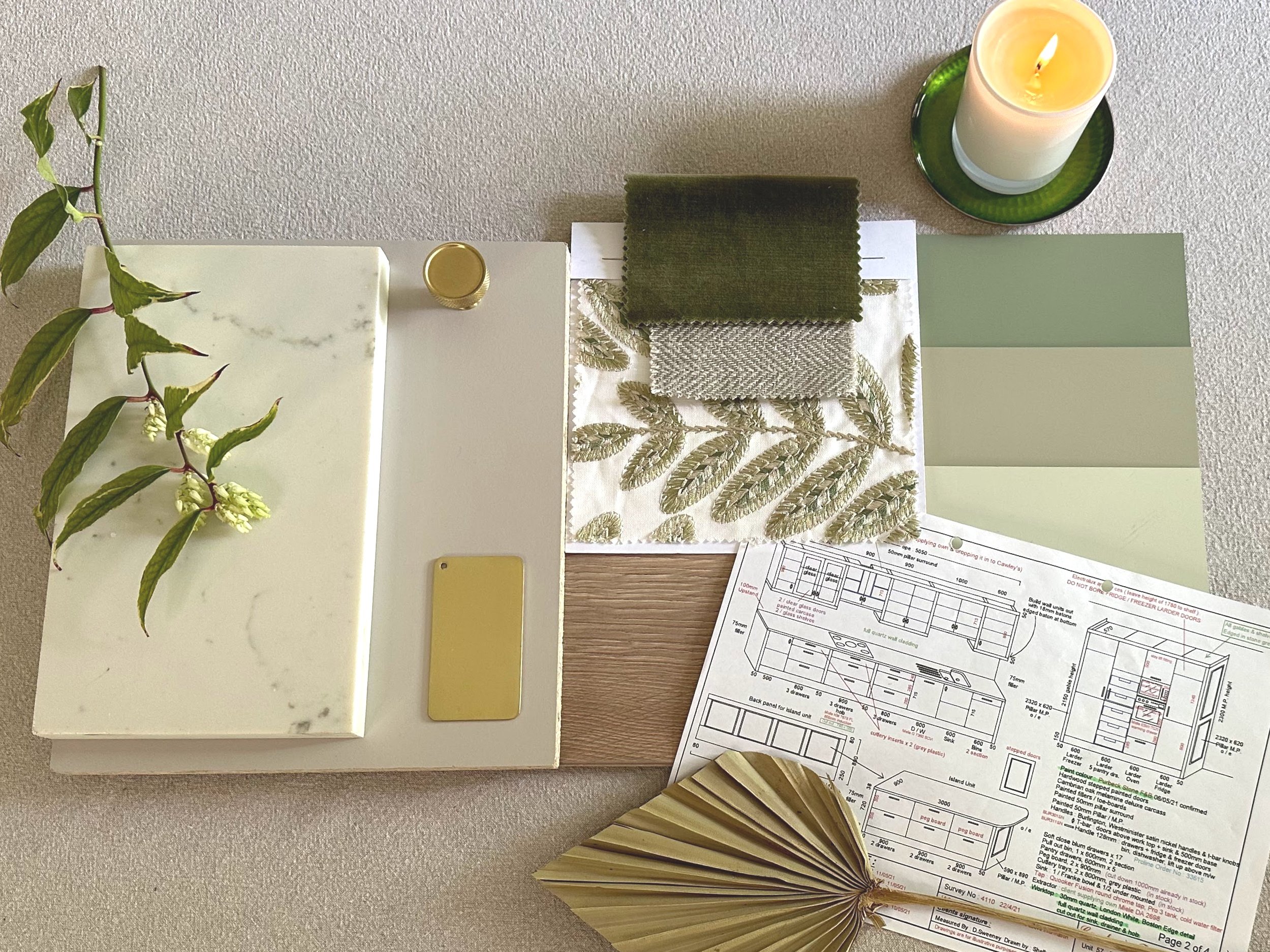 A selection of materials samples assembled by Bobby Lardner, interior designer, in light green tones for a classic kitchen scheme - paint swatches, fabric samples, architectural blueprints, and supporting decorative items on a table.