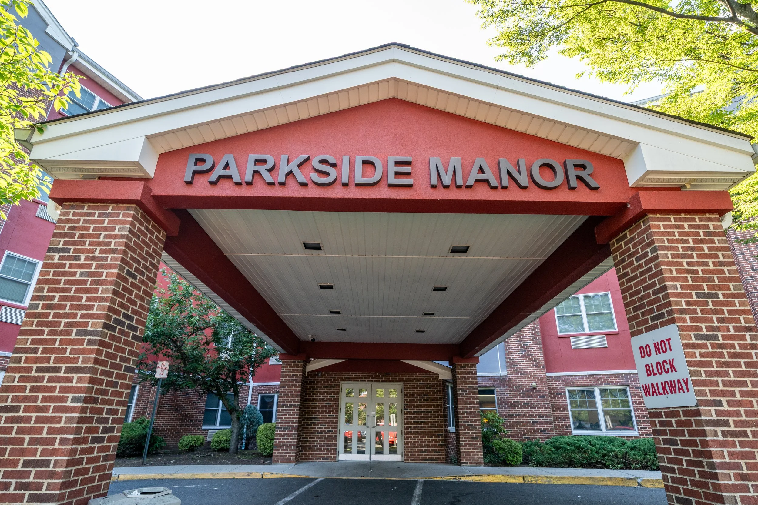 Entrance sign to Parkside Manor apartment complex with brick columns and a covered walkway