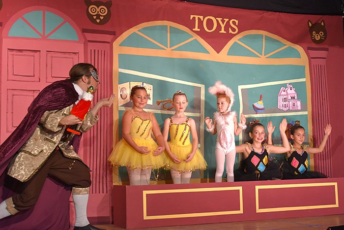 Drosselmeyer blows fairy dust on the toys in the toy store window.