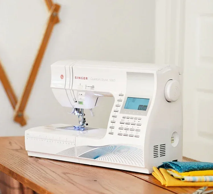 A white sewing machine on a wooden table with yellow and blue fabric pieces beside it.