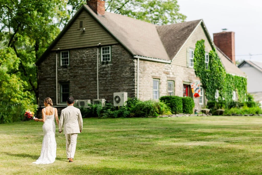 A couple strolls on the lawn outside the stone farmhouse at Black Walnut Farm