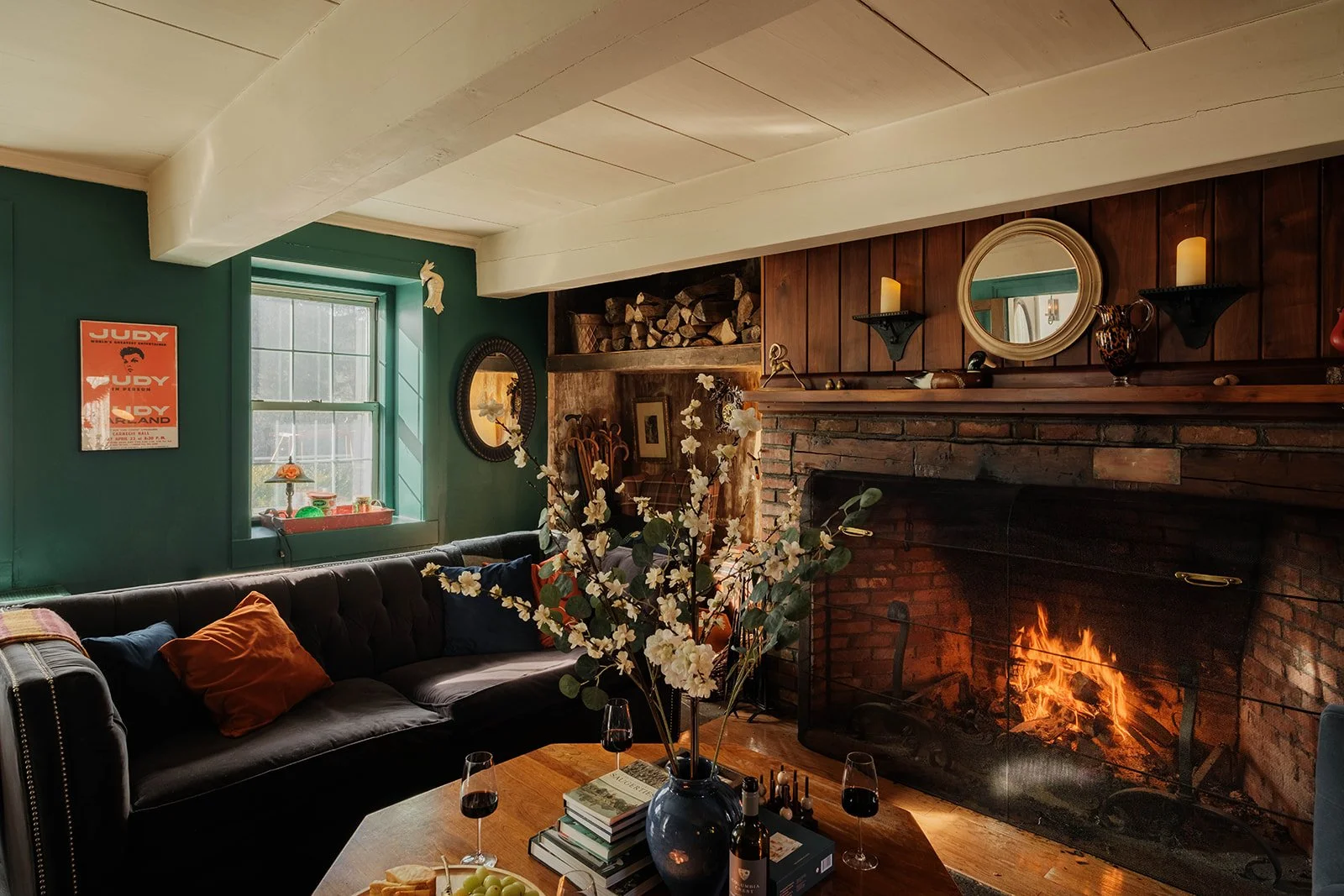 A cozy living room with jewel toned walls, a roaring fire, and lots of antiques at Black Walnut Farm
