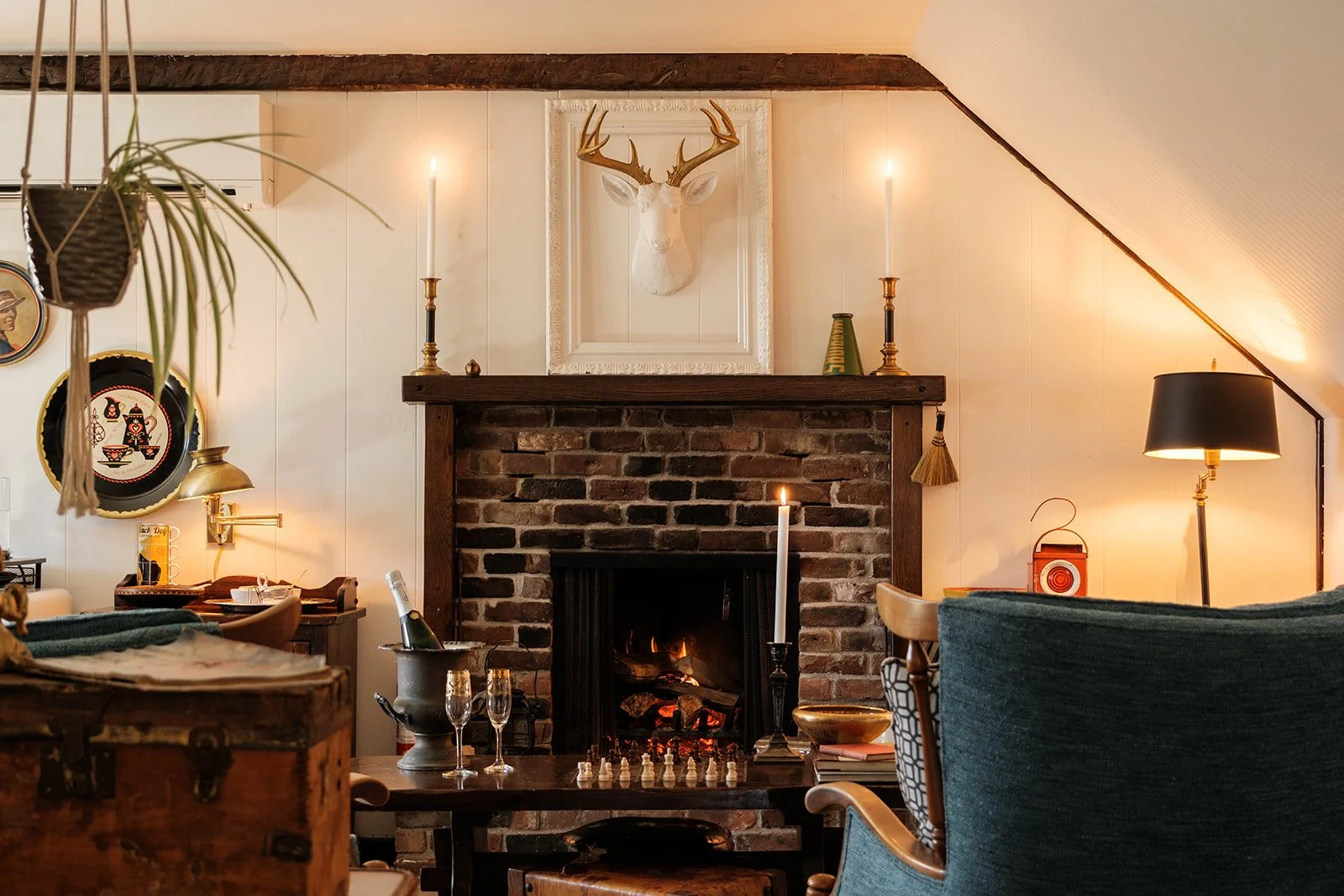 A charming lounge area with cozy chairs and a woodburning fireplace with a chess game and a bottle of Champagne