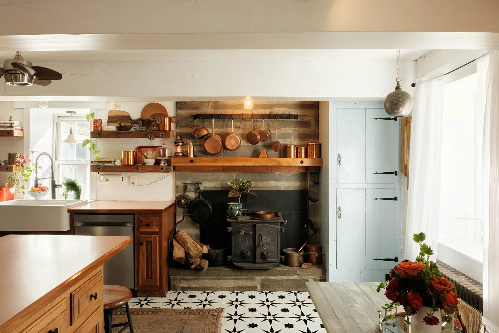 A country kitchen with a wood stove and copper pot collection, and other eclectic decor