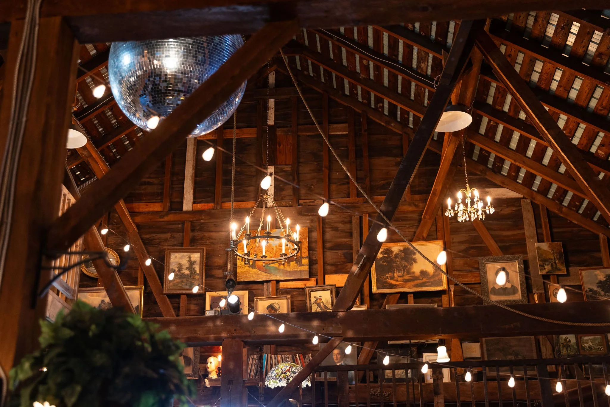 A gallery wall with original beams, vaulted ceilings, string lights and chandeliers at Black Walnut Farm