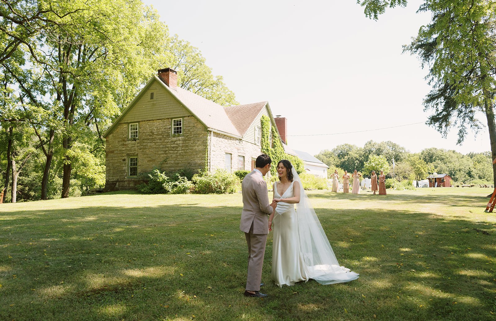 A bride and groom at black walnut farm on a vast green lawn in front of a historic home.
