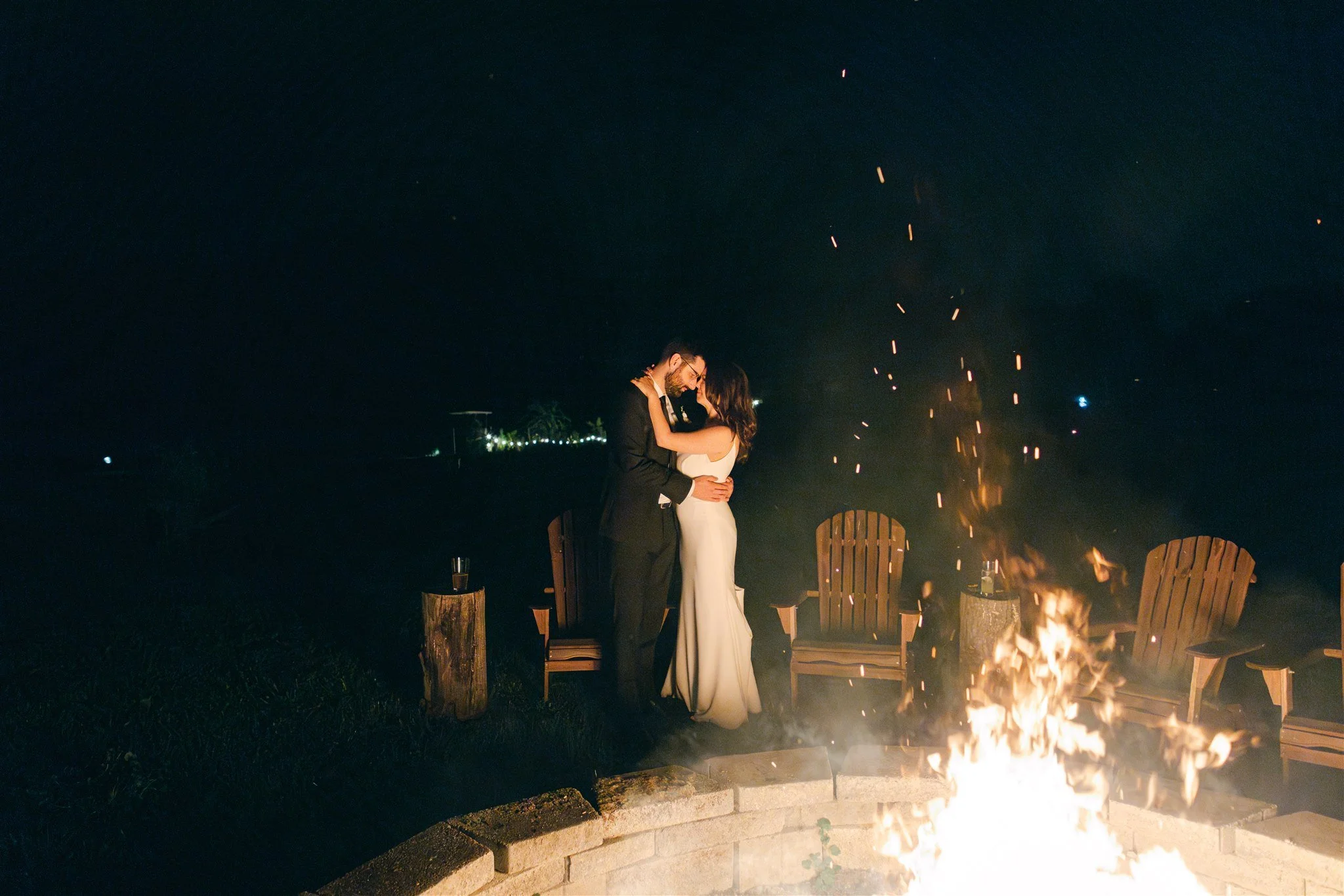 A bride and groom embrace by a sparkling bonfire at wedding venue Black Walnut Farm