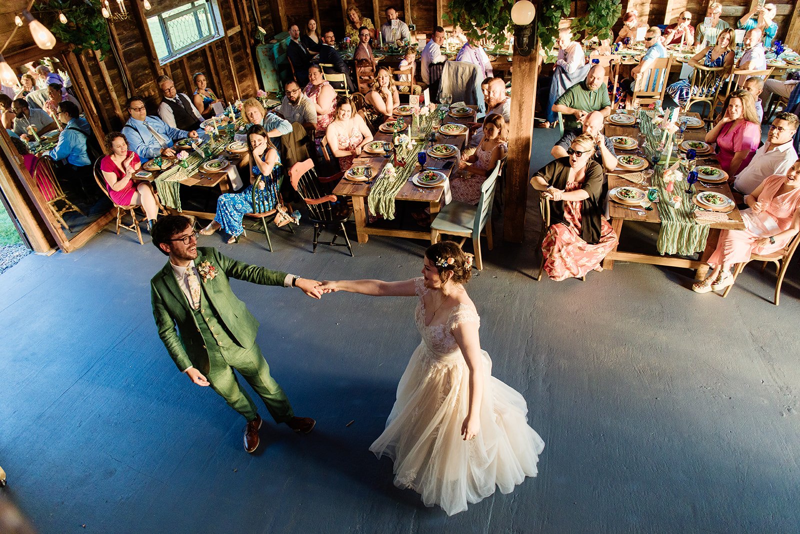 A bride and groom are dancing at their wedding reception, with guests seated at decorated tables watching them.