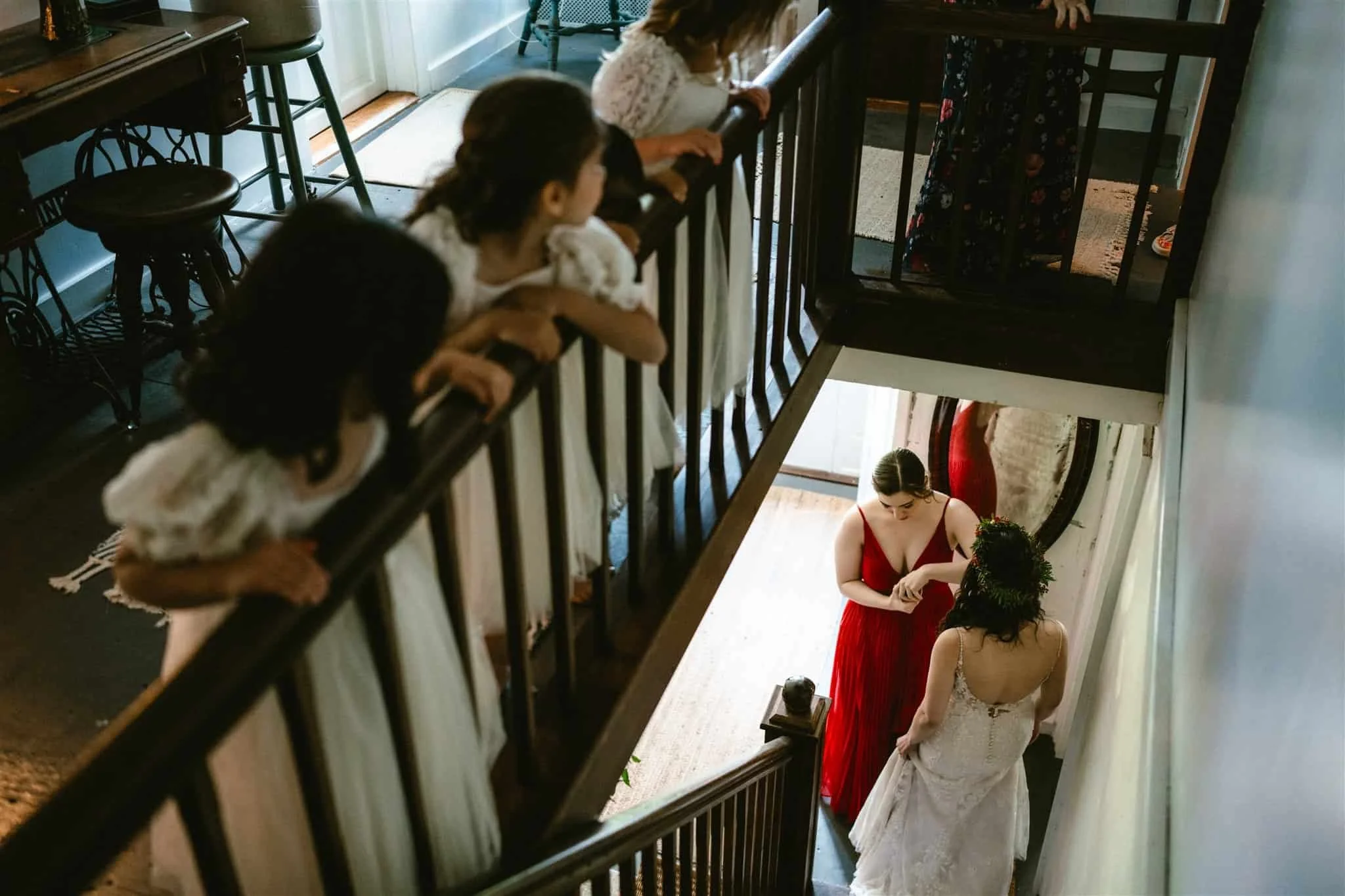 Flower girls looking over a bannister at a bride and bridemaid below at Black Walnut Farm