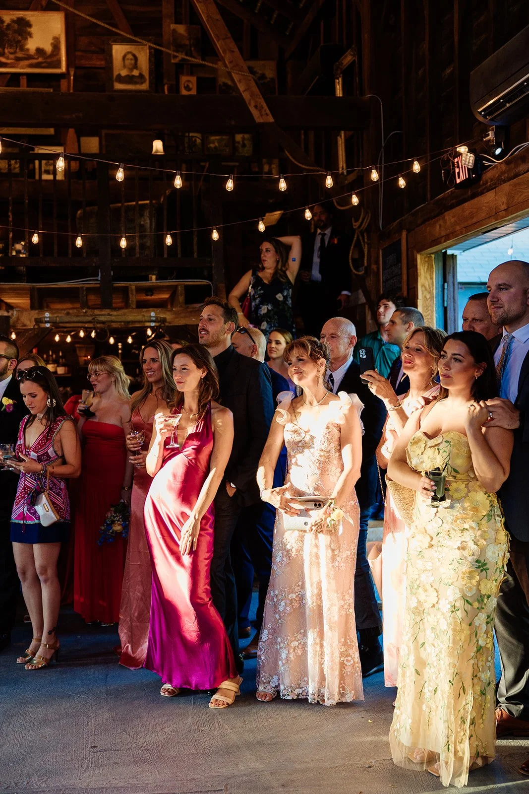 Wedding guests in colorful formalwear look on at a couples' first dance in the Barn at Black Walnut Farm