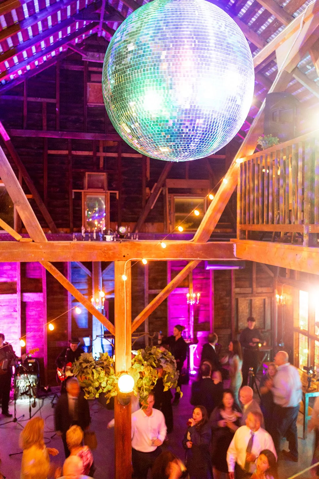 A brightly colored disco ball with dramatic colorful uplight around the barn at Black Walnut Farm