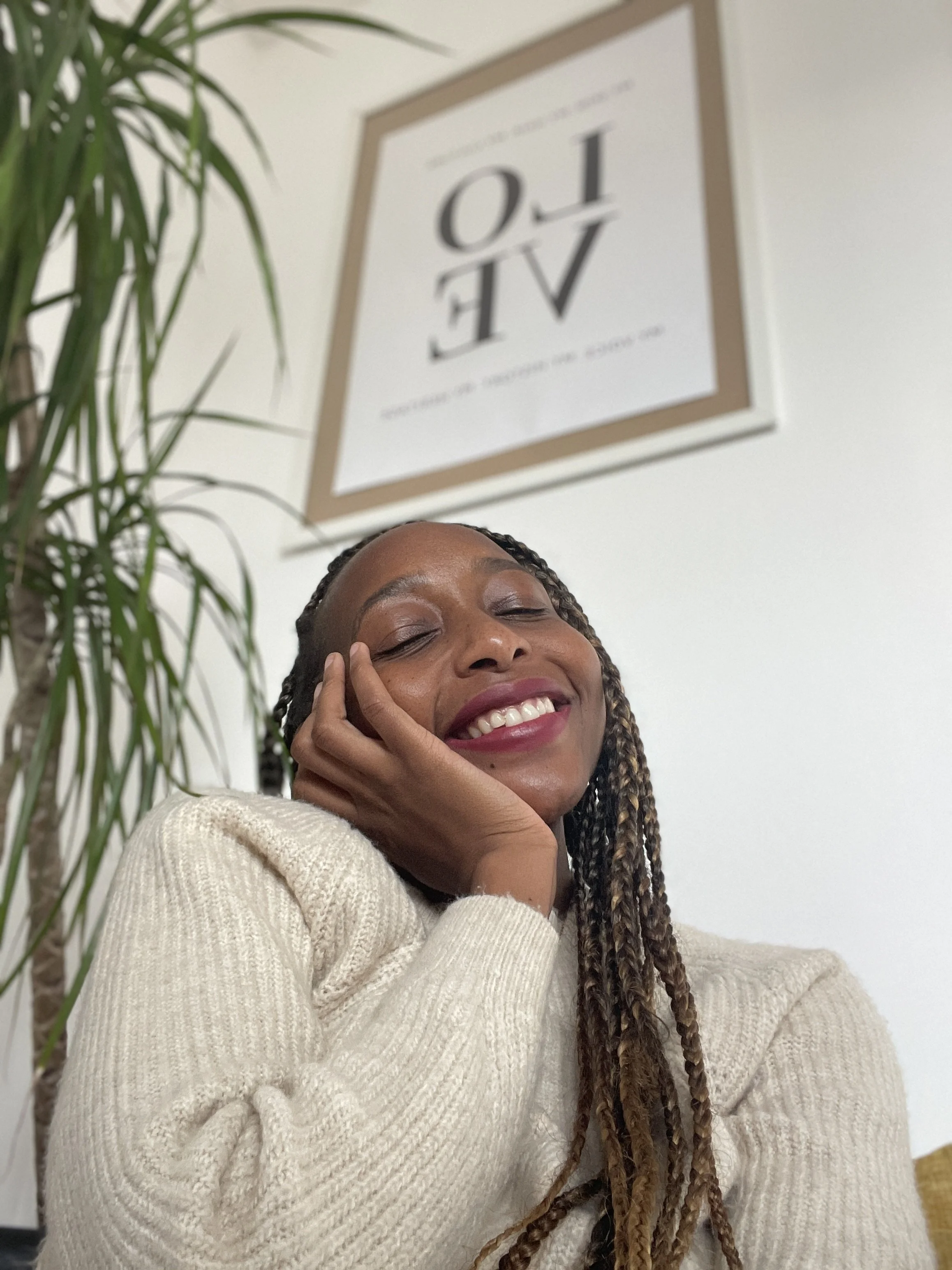 A woman relaxing in a flower-filled bathtub with a view of lush greenery outside and a statue of a woman on the side.