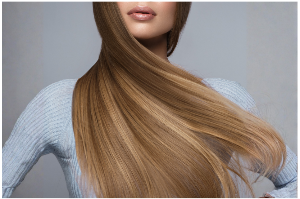 Close-up of a woman with long, straight, light brown hair wearing a light blue sweater.
