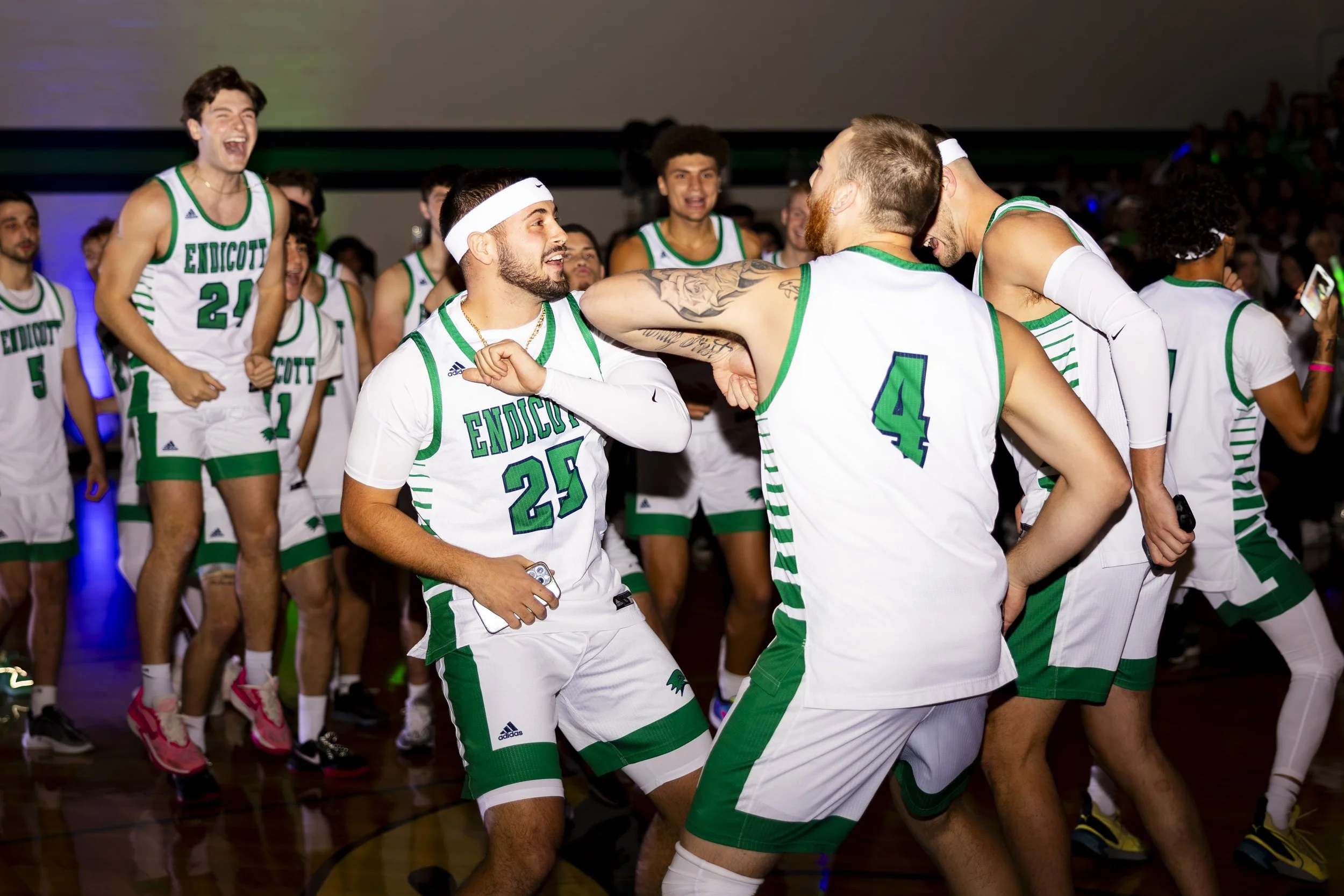 A group of basketball players in green and white jerseys celebrating and dancing on the court.