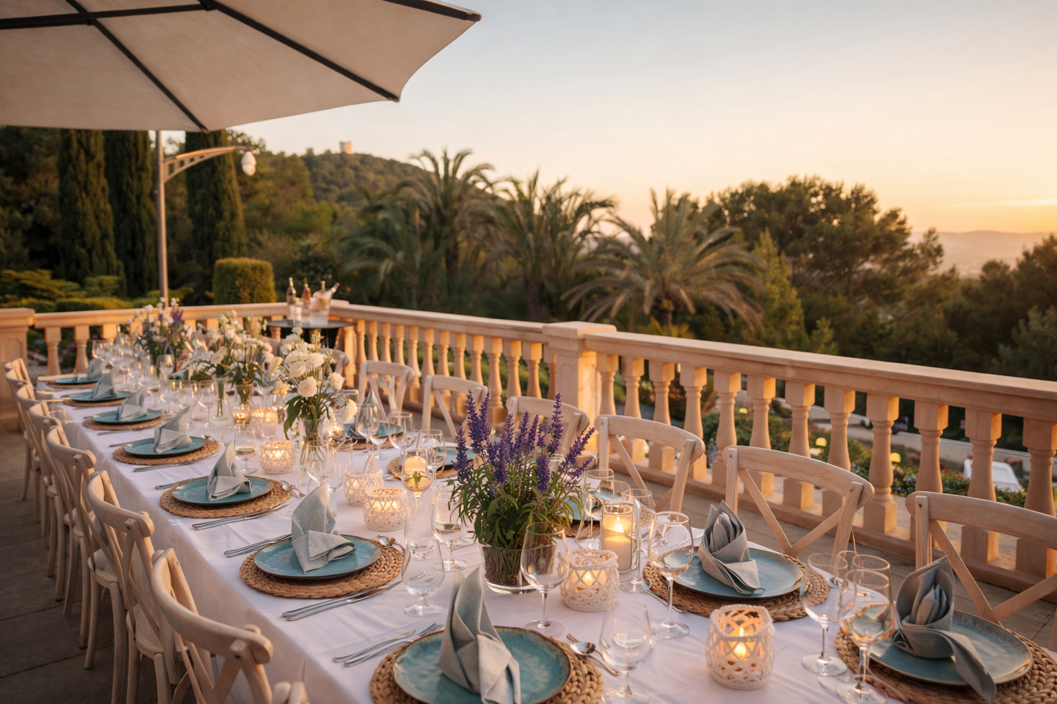 Outdoor Mallorca private chef dining table set for a formal event with candles, flowers, plates, glasses, and napkins on a balcony overlooking trees and a sunset sky.