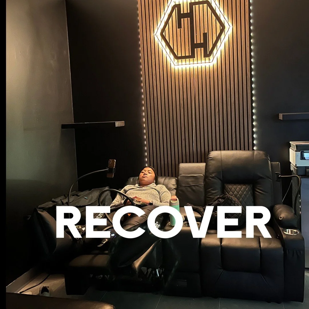 RECOVER: a patient resting in a recliner with compression boots on, under the lit Health Hive sign