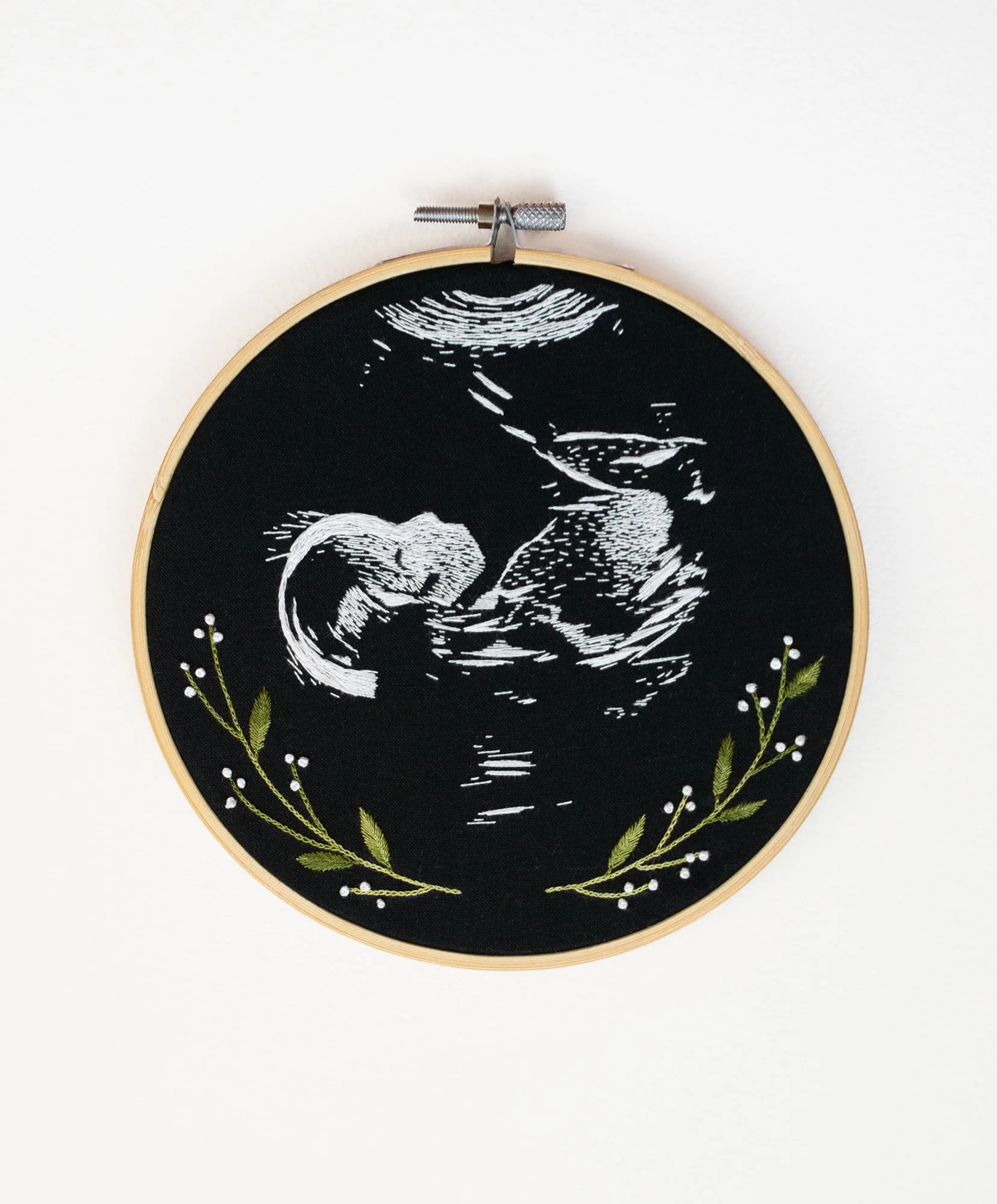 Hooped hand embroidery art of a natal ultrasound on black fabric