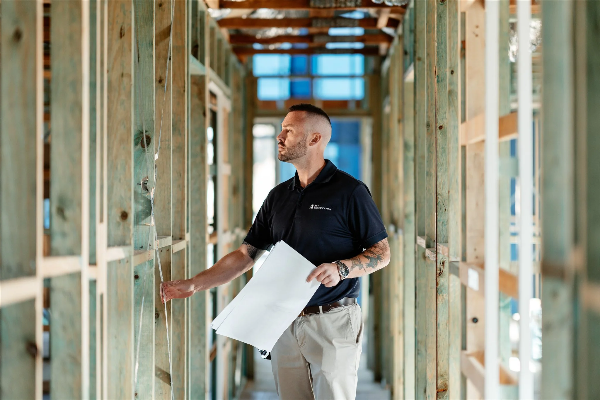 Construction worker at a building site inspecting the framing with blueprints in hand.