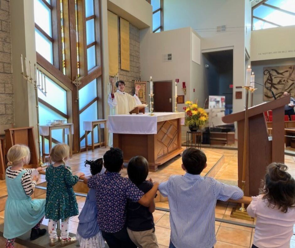 Two young children gazing wonderingly at the altar as an Episcopal Deacon prepares for communion