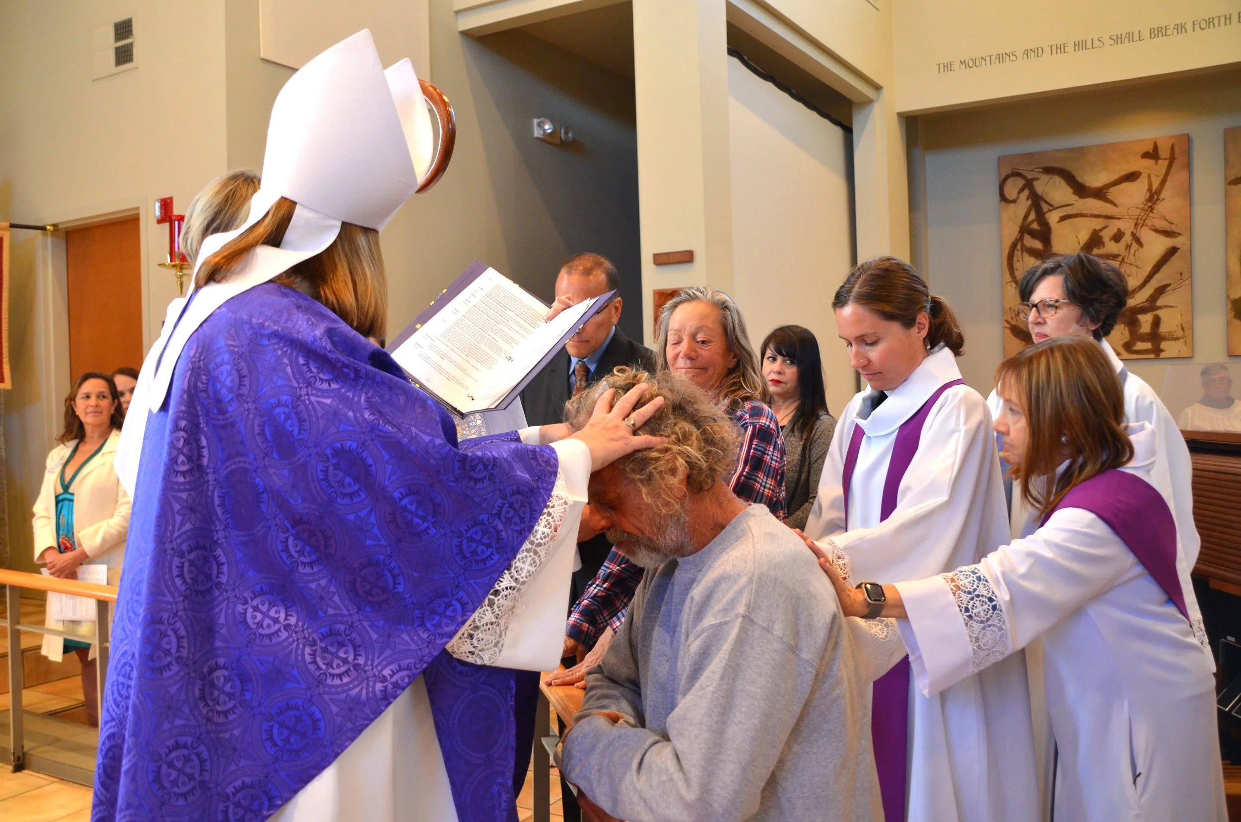 Female Priest baptizing a baby with children watching at St. Andrew's Episcopal Church Encinitas