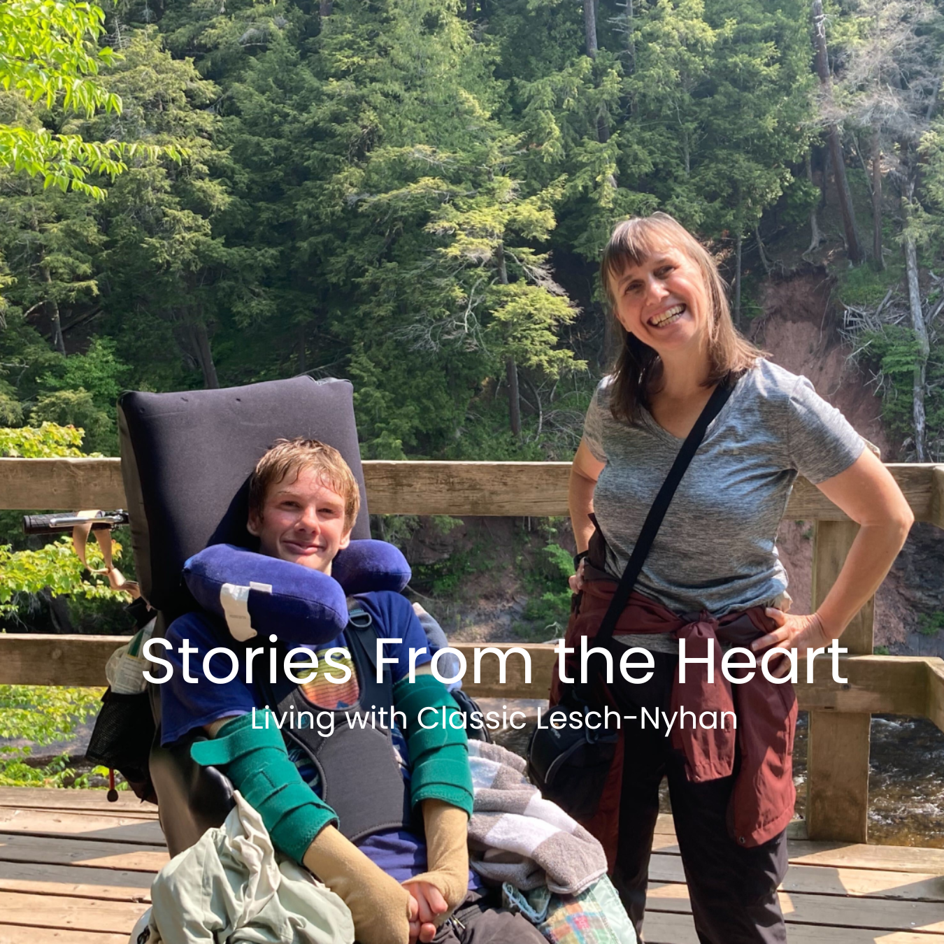 A woman and a young man with Lesch-Nyhan smiling outdoors on a wooden deck with a forested background. The young man is in a wheelchair with a neck pillow and green safety devices on his legs. Stories from the heart.