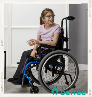 A young girl siting in a wheel chair wearing a light pink t-shirt and befree adaptive pants