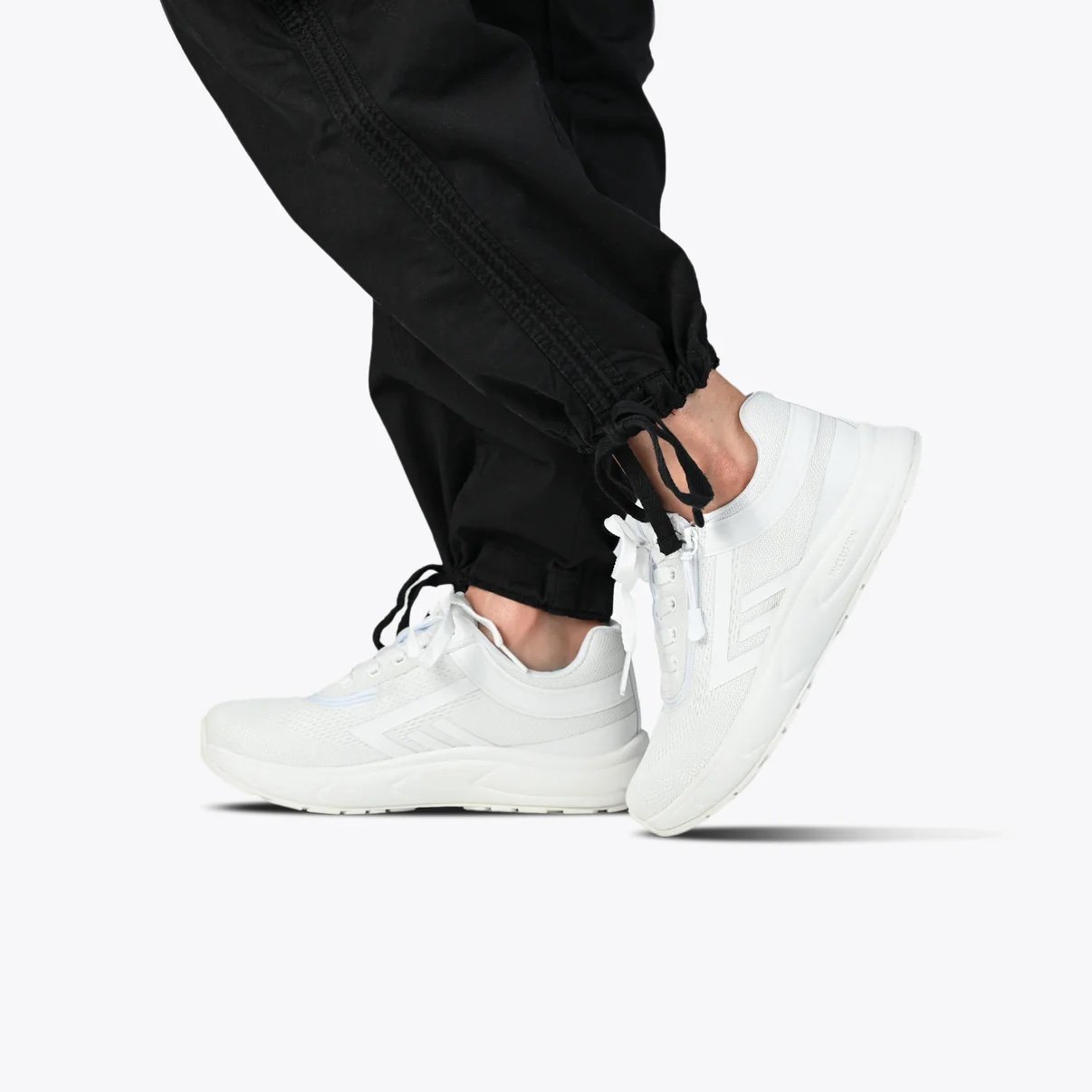BILLY women's sport inclusion sneaker shown in all white modeled on a woman wearing black jogger pants