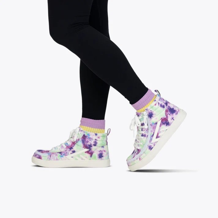 BILLY kids adaptive high top sneaker in a purple and green watercolor shown on a kid wearing black leggings and purple and yellow socks