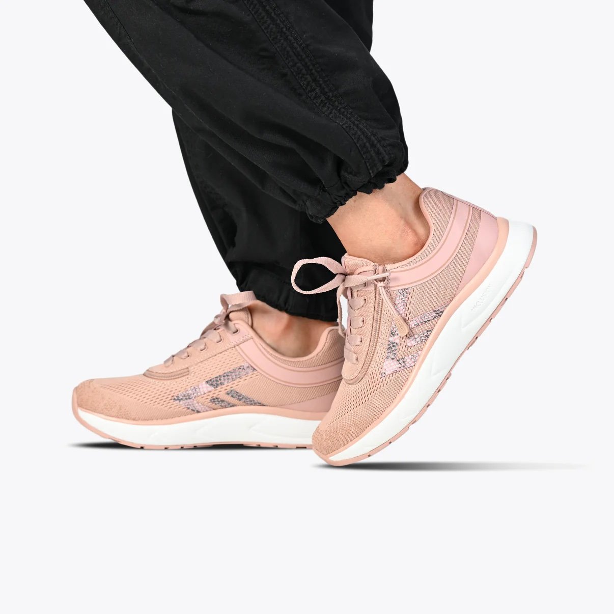 BILLY women's sport inclusion sneaker in a blush pink modeled on a woman wearing black jogger pants