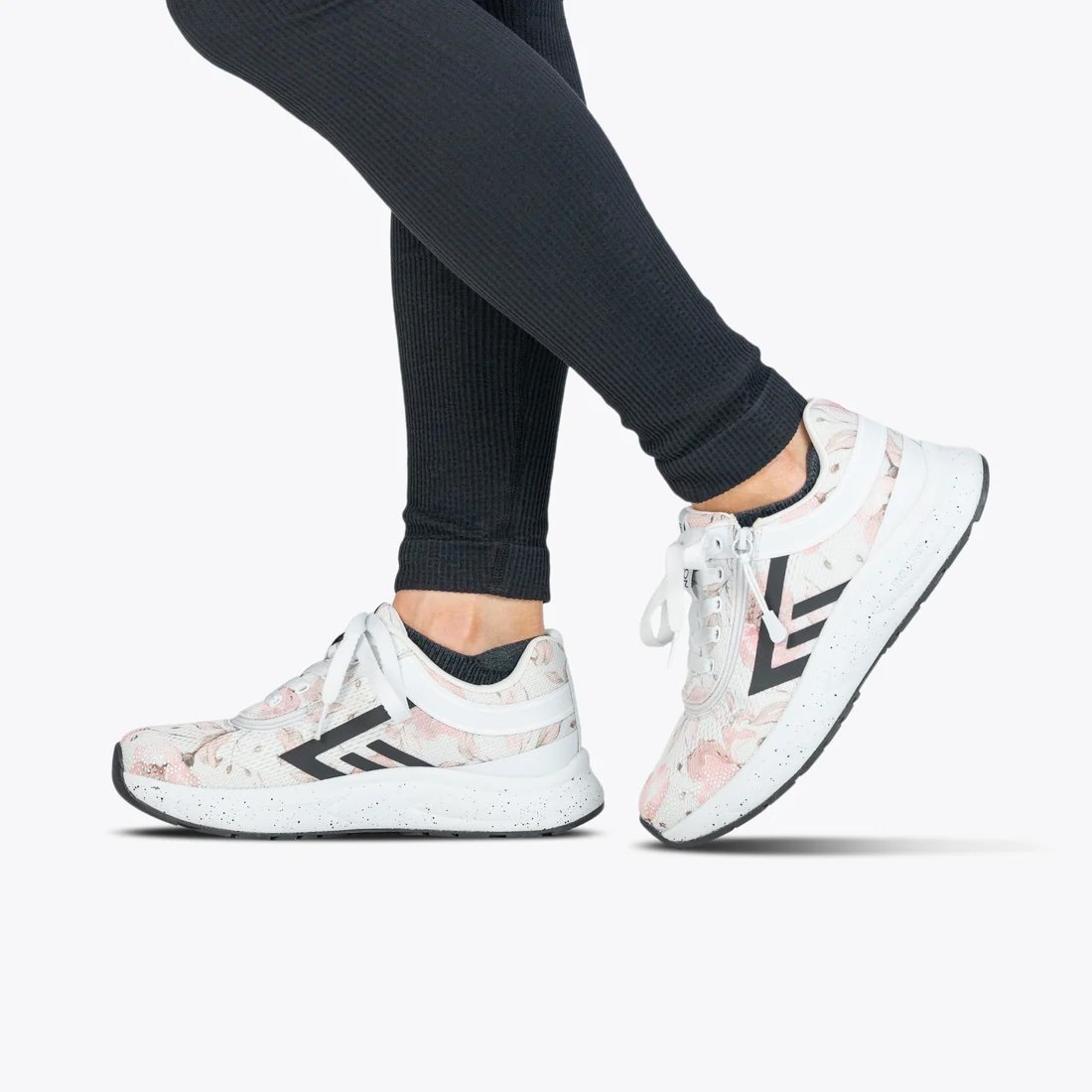 BILLY women's white sneaker with a light pink floral pattern and black accents modeled on a woman wearing black leggings