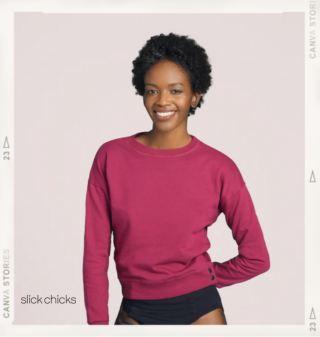 A woman smiling at the camera wearing a deep pink crewneck adaptive sweatshirt that has buttons at the seam near the hip