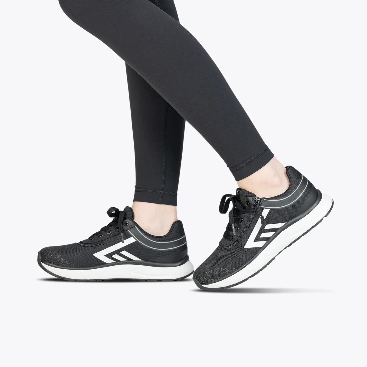 BILLY women's sneaker in black wth white accents and rubber sole modeled by a woman wearing black leggings