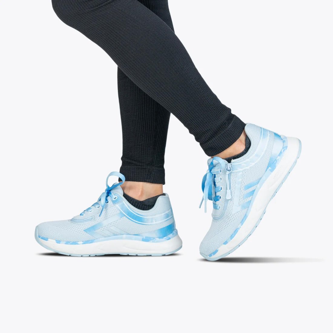 BILLY women's sneaker in a very light blue with accents that are a darker marbled blue modeled on a woman wearing black leggings