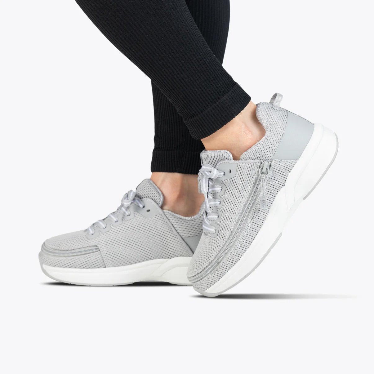 the BILLY women's limitless sneaker in a light grey shown on a model wearing black pants