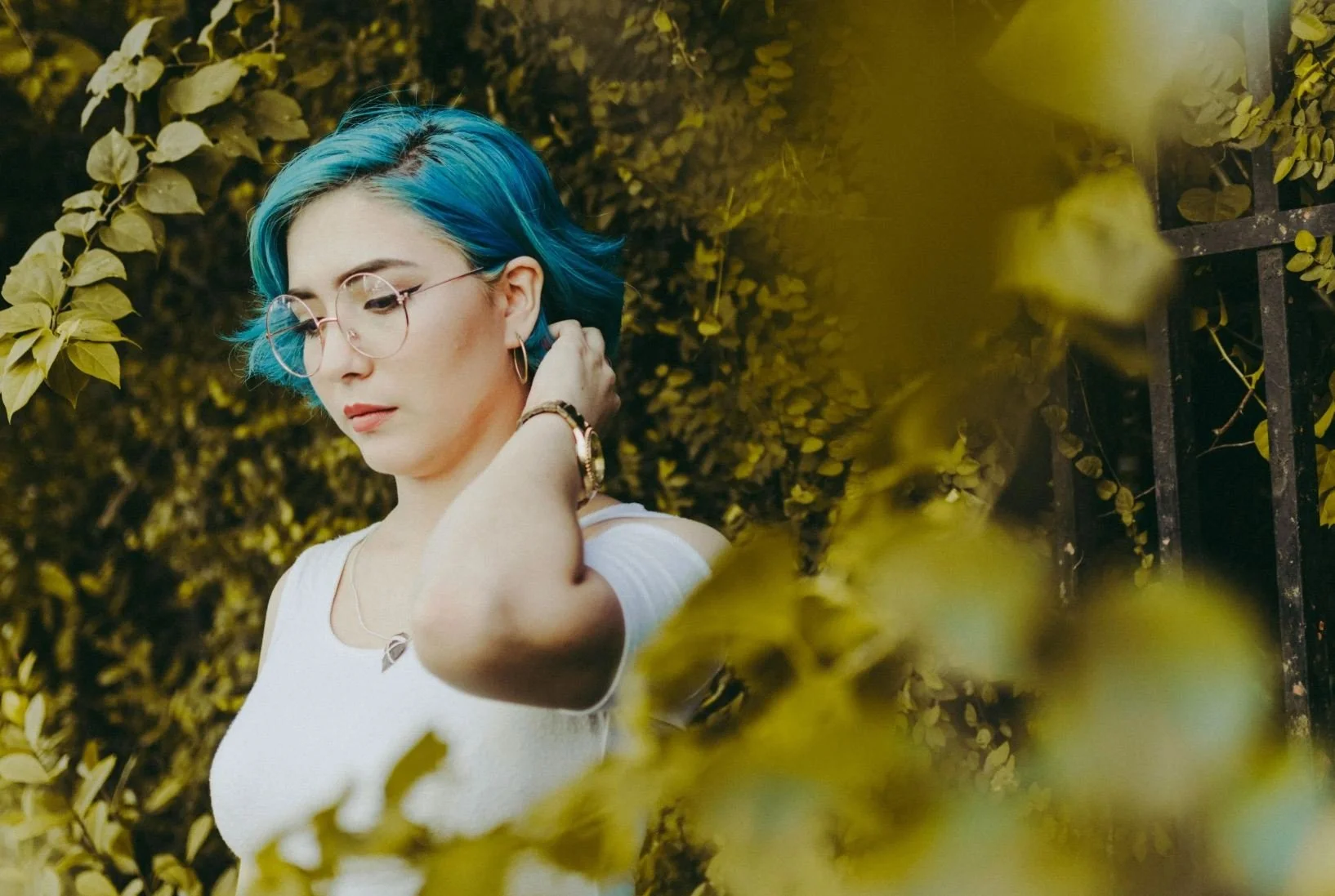 Woman with blue hair stands in front of trees looking uncomfortable as if she has PMDD.