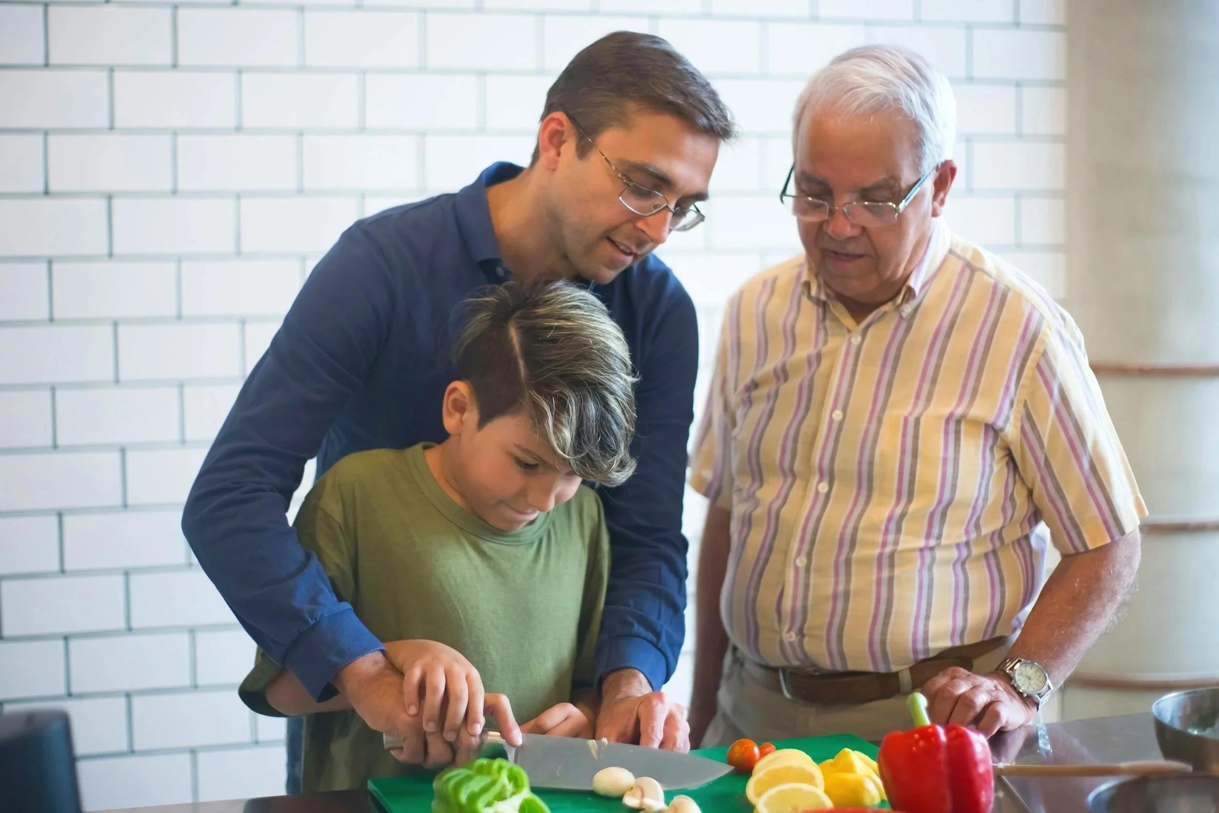 Dad, grandpa, and son working together to chop peppers.