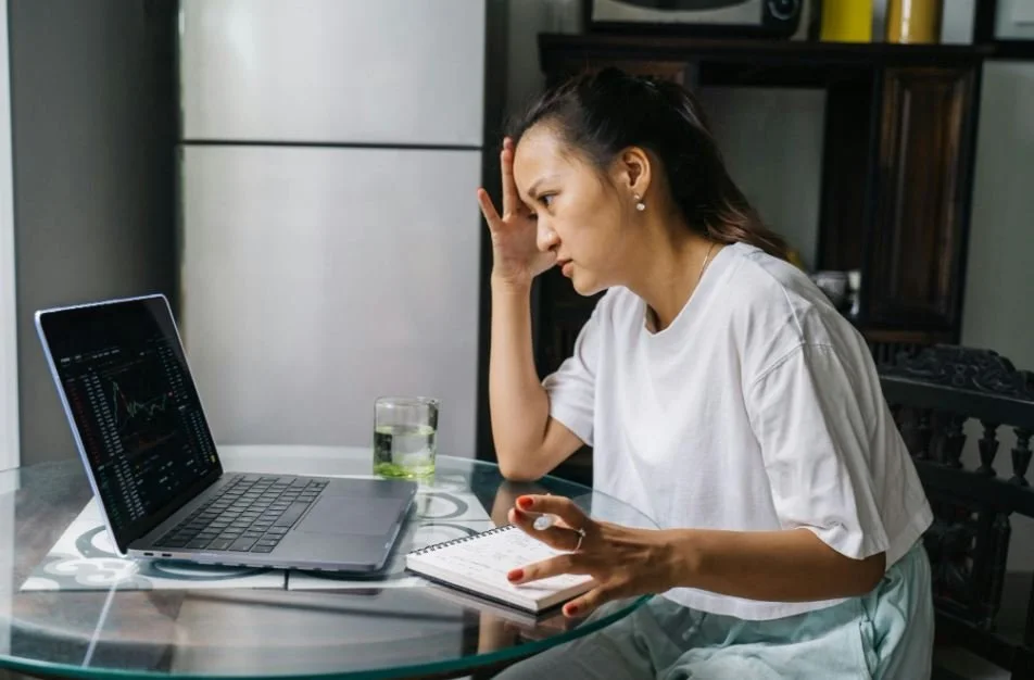 Woman sits at computer looking worried as if she has OCD.