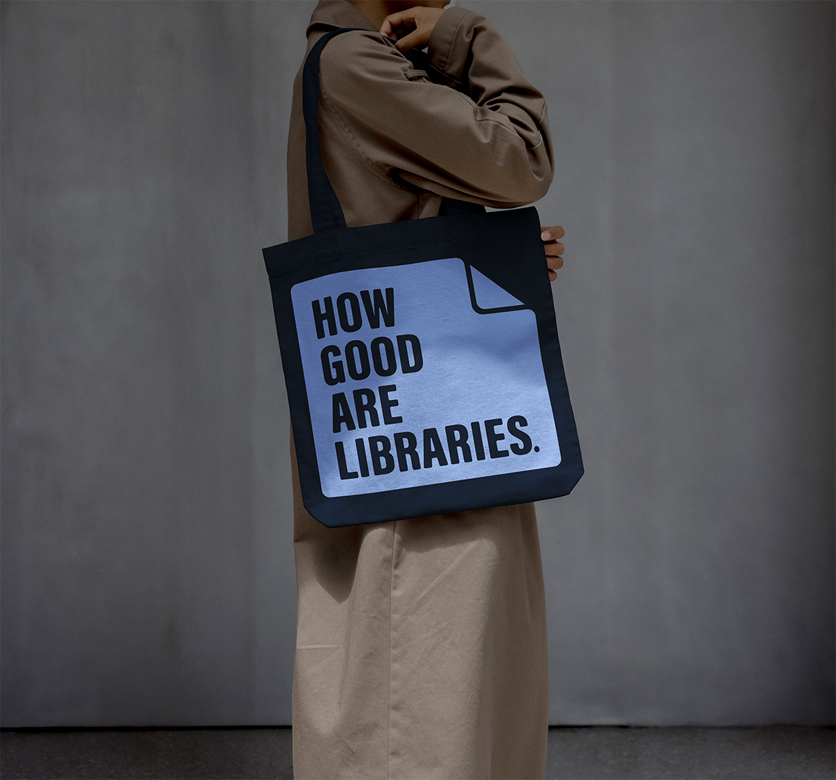 Person holding a tote bag with a sign that says "How good are libraries."
