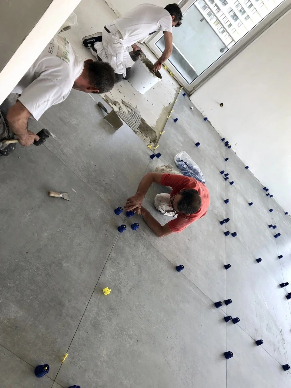 Chantier : pose du carrelage gris grand format au sol par les carreleurs