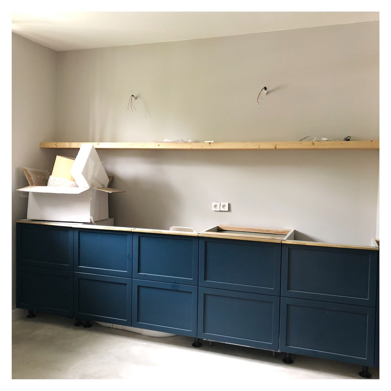Cuisine sur mesure bleu marine en cours de finition, étagère en chêne et plinthe en laiton