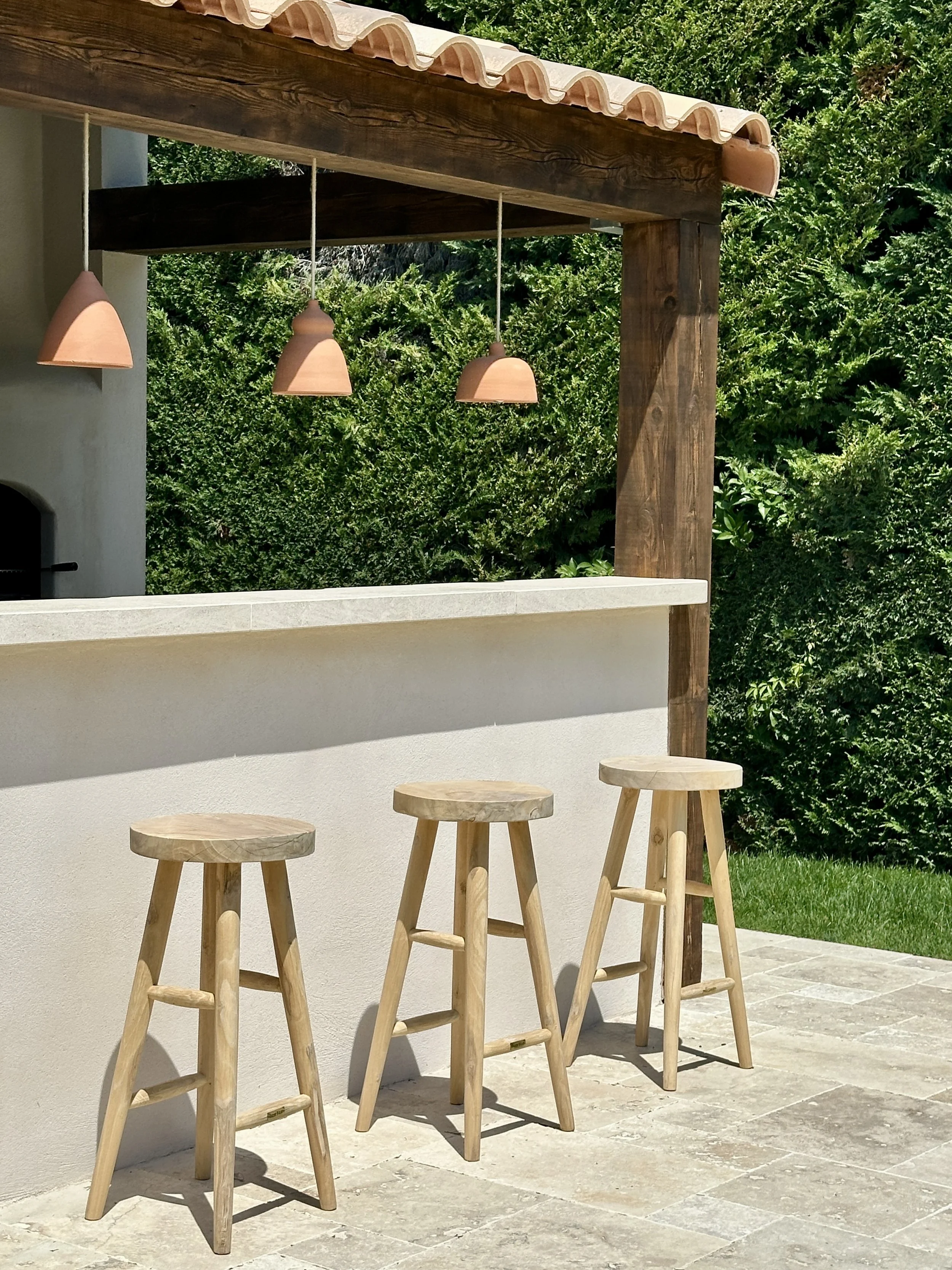 Le bar de la cuisine d'été avec ses tabourets en bois et ses suspensions en terre cuite
