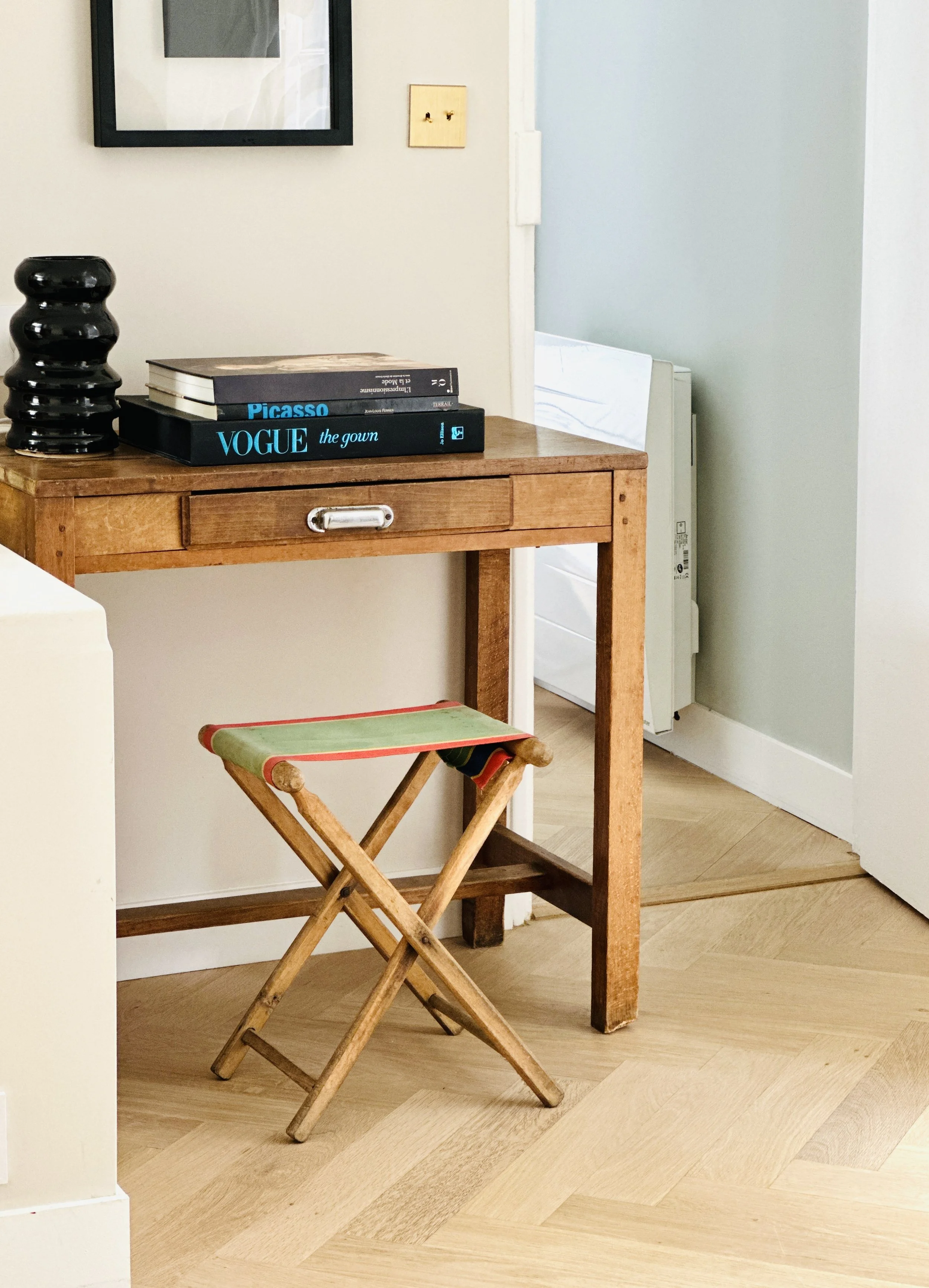 Bureau en bois ancien avec tabouret pliant, pile de livres et parquet à chevrons