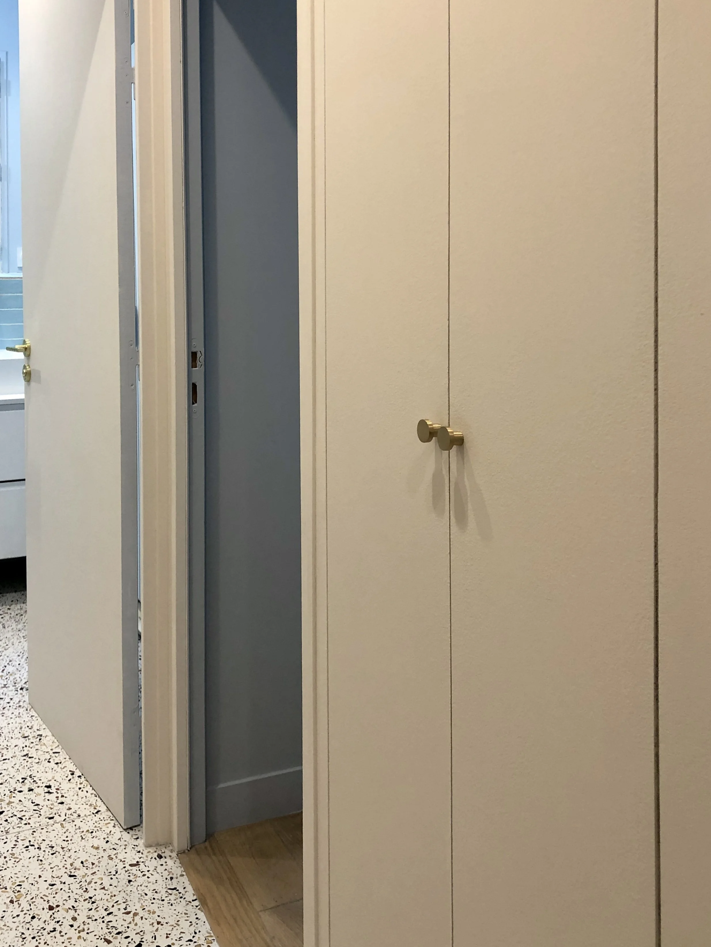 Couloir équipé de placards sur mesure toute hauteur sur toute sa longueur, sol en terrazzo