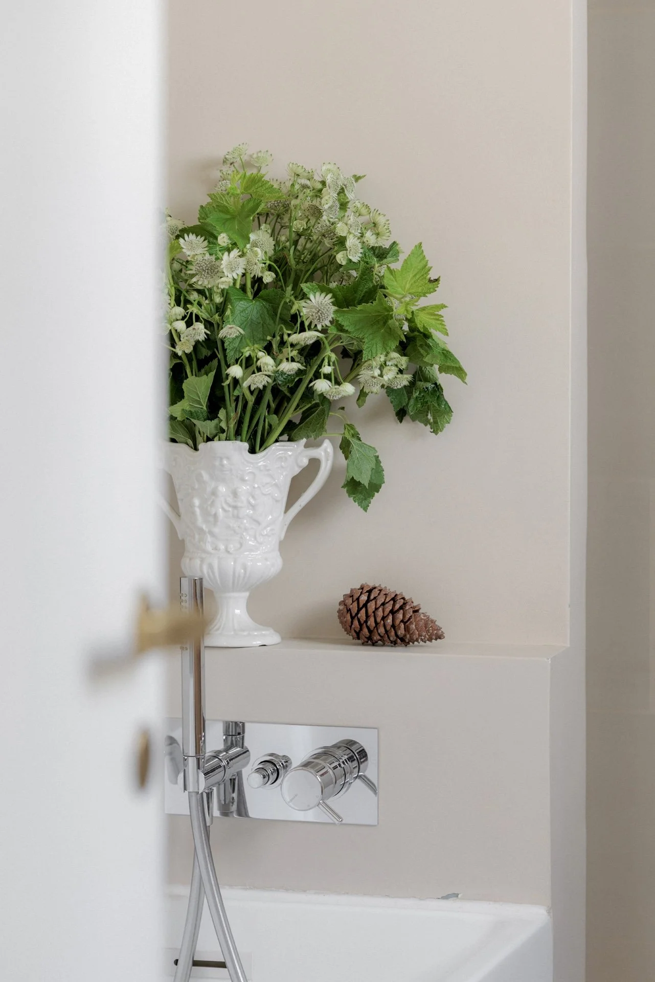 Badezimmer-Wandnische mit dekorativer Vase, Blumen und Chrom-Armatur